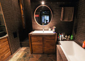 Мебель в ванной комнате, как и в кухне, сделана на заказ, а круглое зеркало в тон — из Ikea.