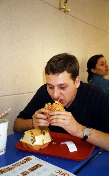 Юрий за поеданием гамбургера в ресторане своей любимой финской сети фастфуда «Кэрролс»