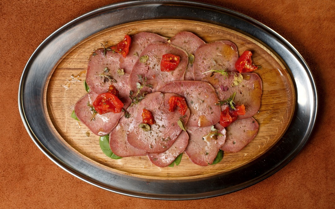 Cлайсы языка с каперсами и вялеными томатами в ресторане BeefZavod