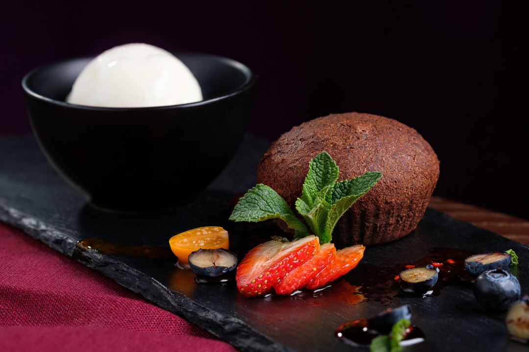 Шоколадный фондан подается со сливочным мороженым, свежей клубникой, физалисом и сладким облепиховым соусом