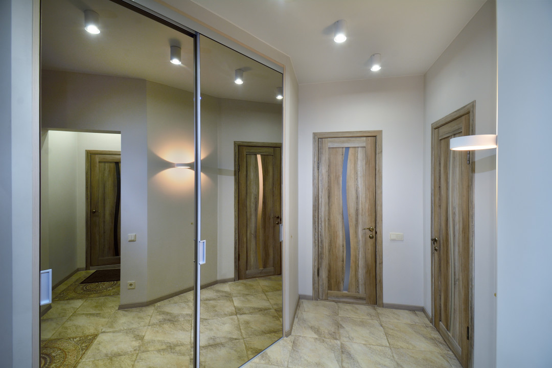 Функциональность и эстетика. Шкаф с зеркальными дверями зрительно расширяет пространство (Mr. Doors). Минималистичные накладные светильники-бра можно