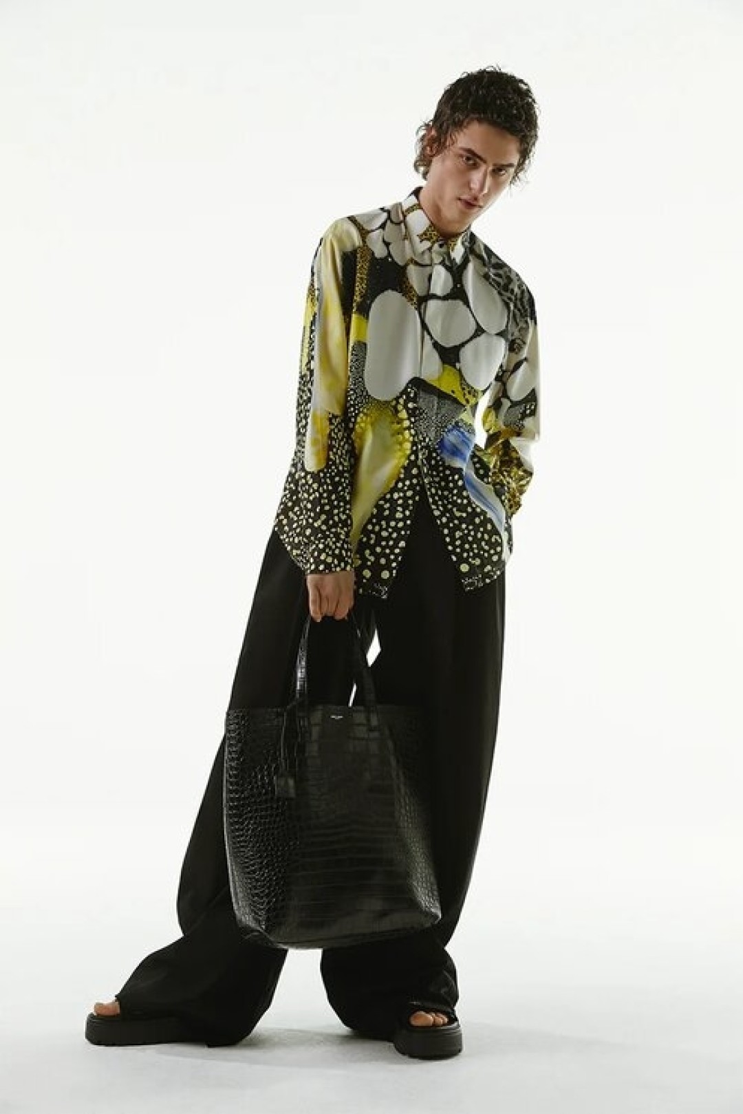 Рубашка Berluti, 113 000 руб.,; брюки Bottega Veneta, 76 250 руб., сумка Saint Laurent, 110 500 руб., сандалии Valentino Garavani, 55 700 руб.