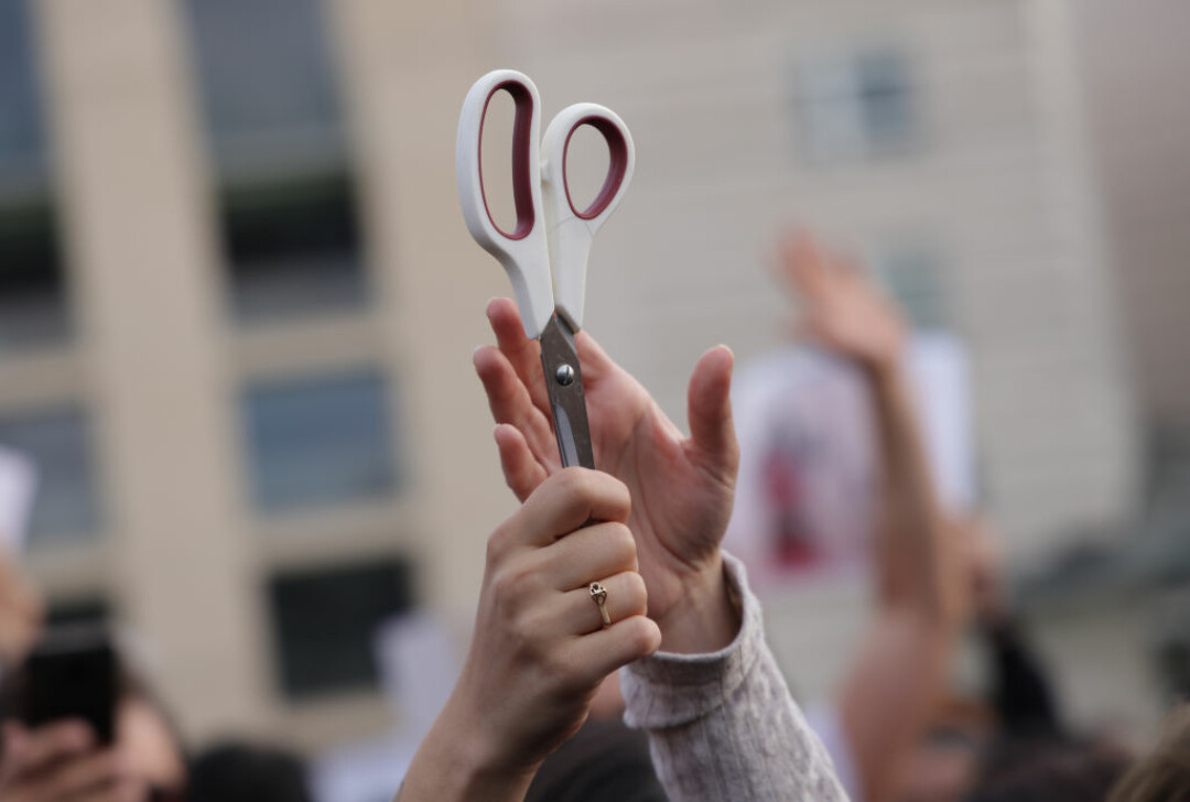 Протестующие в Берлине женщины держат ножницы, подстригая друг другу волосы в знак солидарности с женщинами в Иране во время демонстрации против