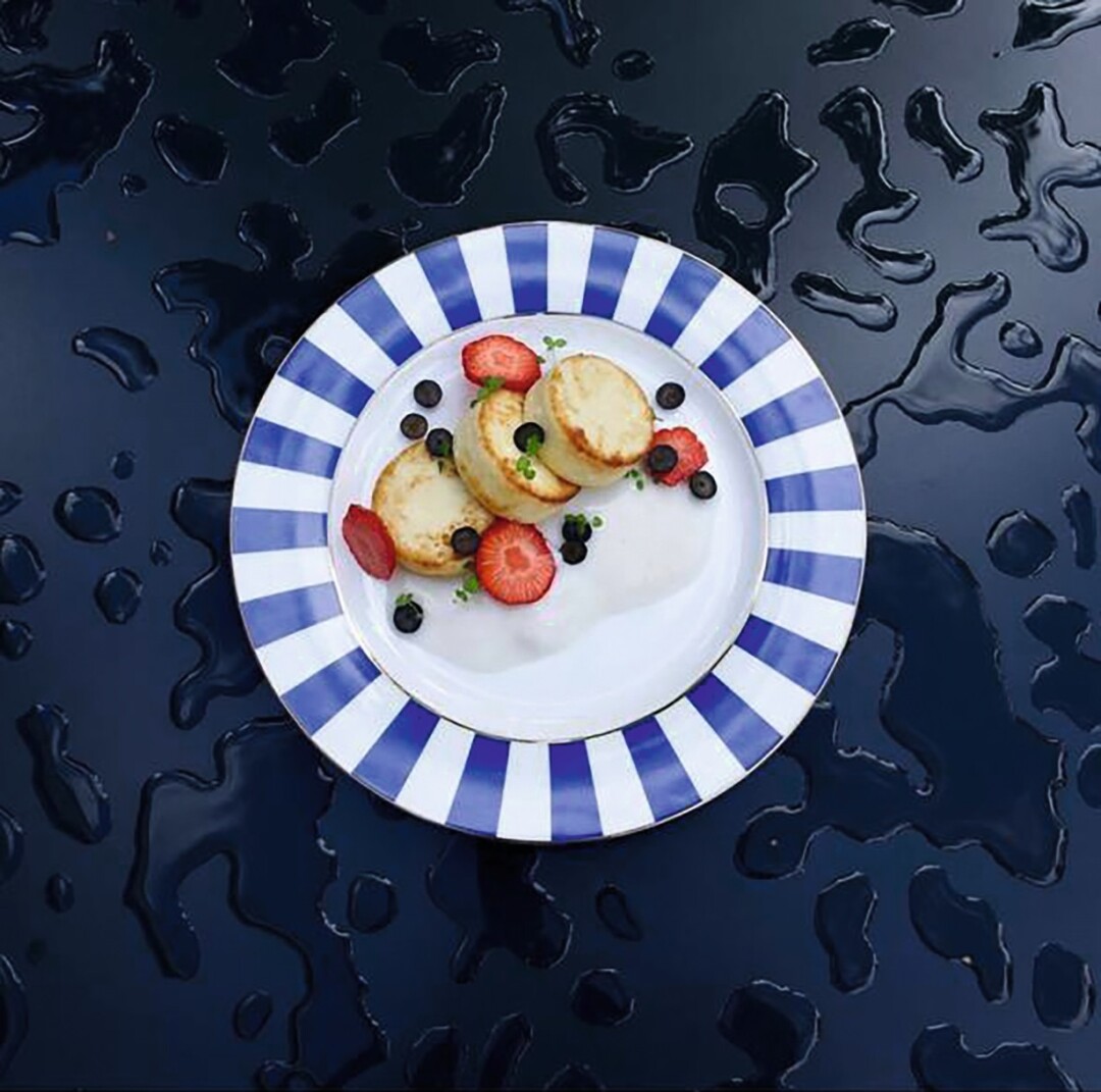 Сырники с кокосовой сгущенкой и ягодами на костяном фарфоре Stoppard поймали в кадр на столе после дождя