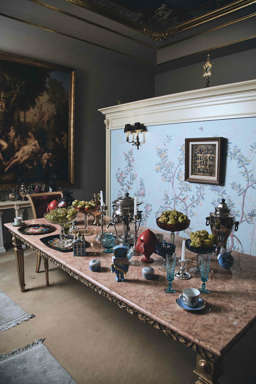 Стол сервирован елочными украшениями, хрусталем и чайными парами с Щелкунчиком, все — из интерьерной линии Axenoff Home. На стене — обои ручной работы