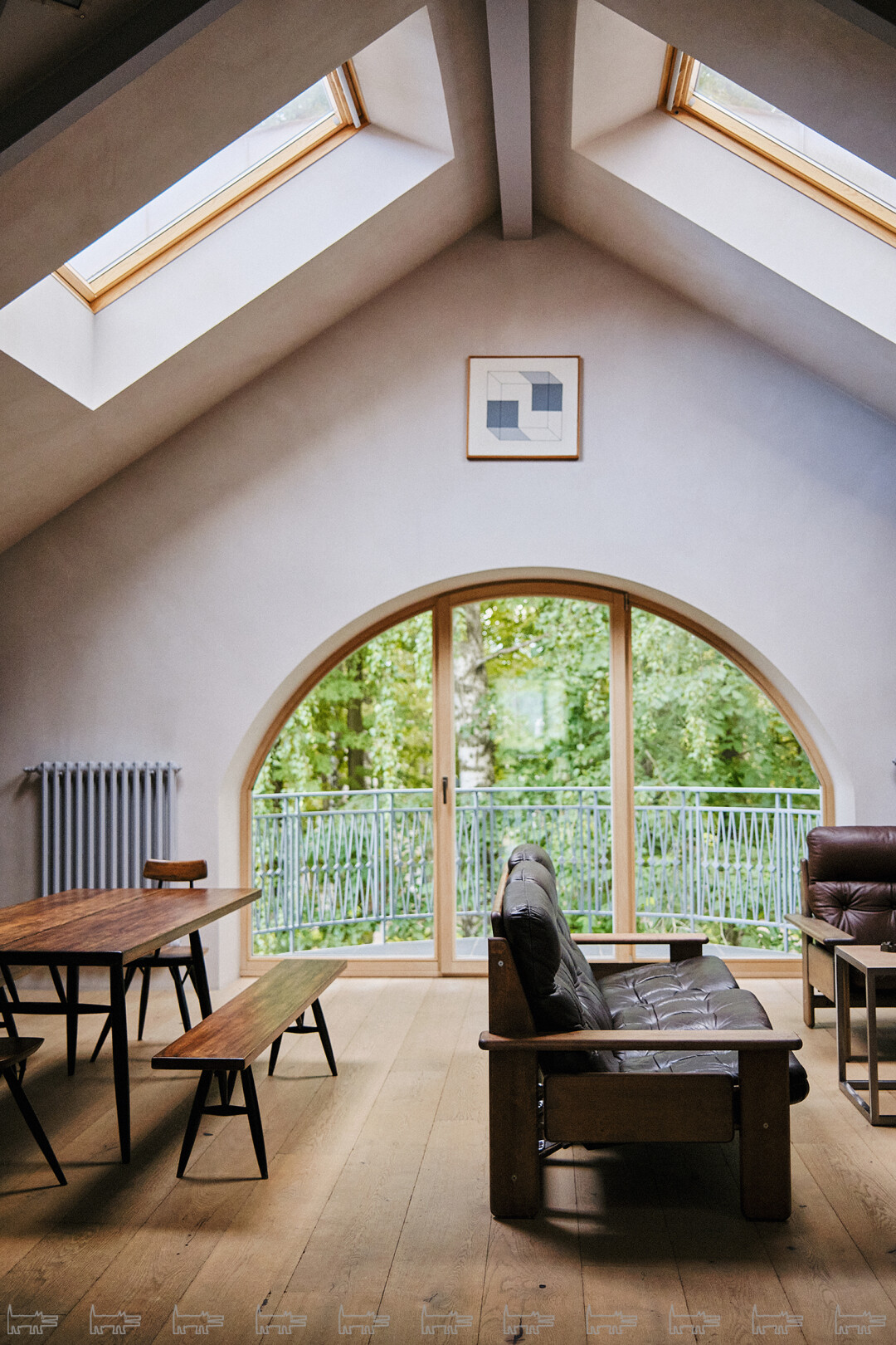 В гостиной квартиры в Павловске много естественного света благодаря мансардным окнам и арочному окну в пол. Над ним расположилась работа