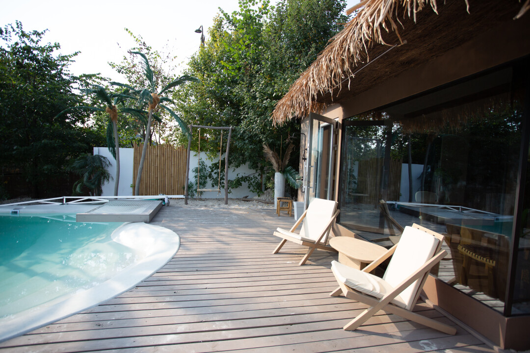 Придомовая территория глэмпинга с декоративными пальмами и бассейном с подогревом