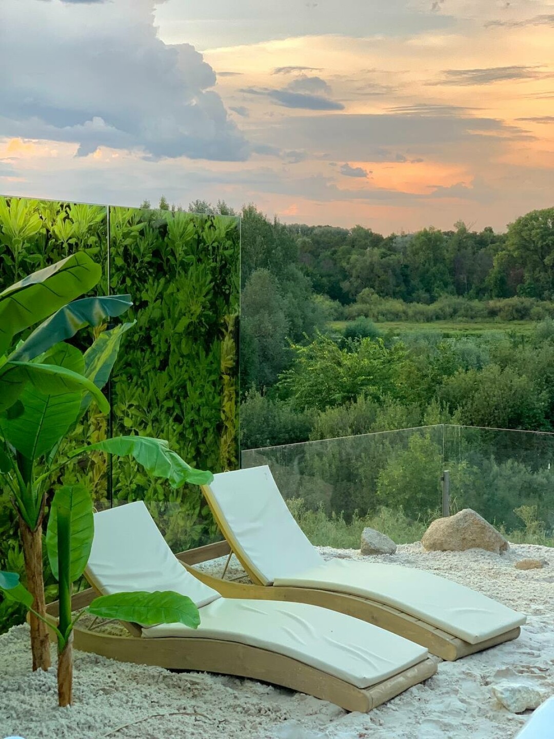 Лаунж-зона с декоративными пальмами, лежаками и пляжным песком