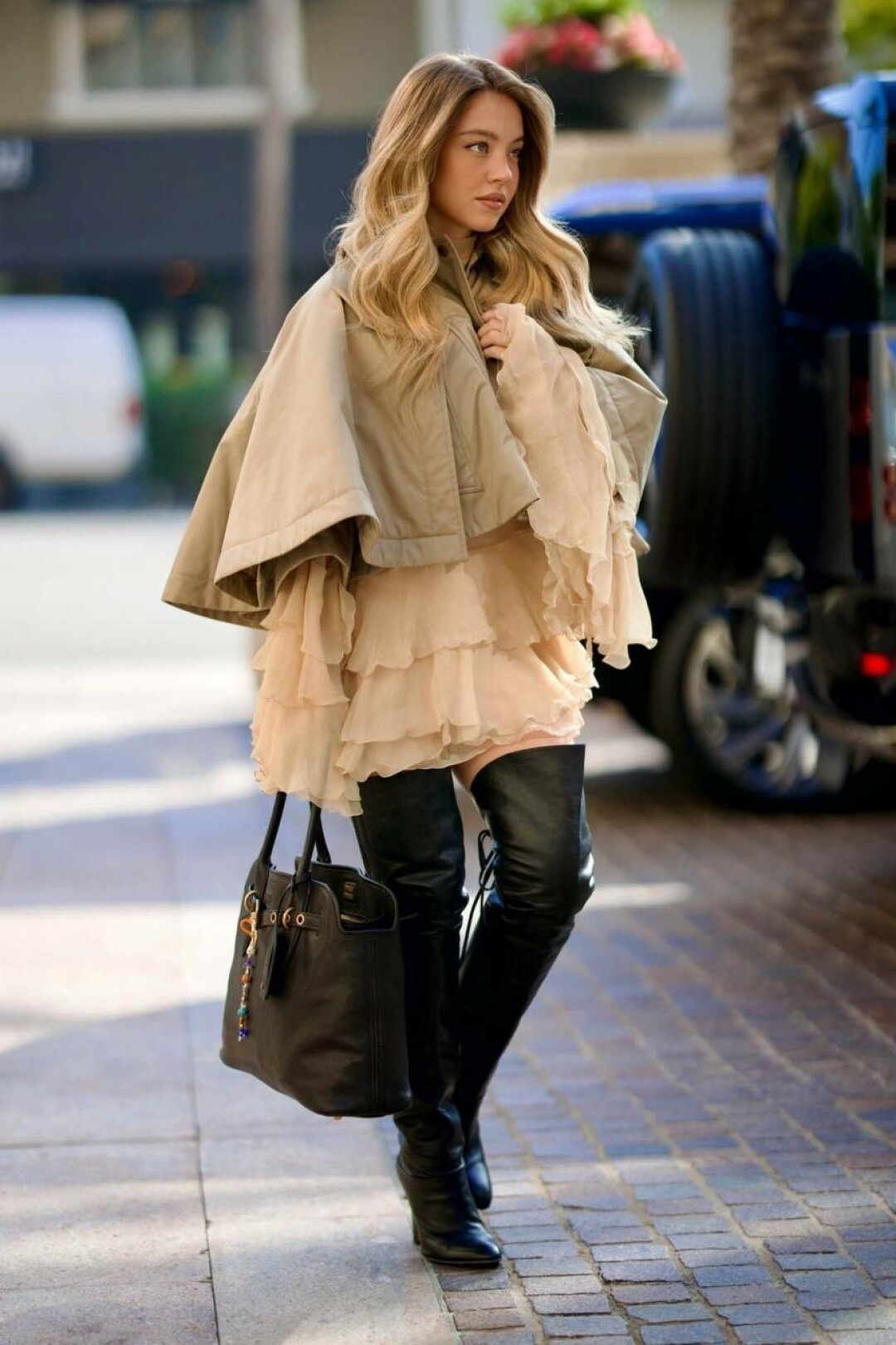 Актриса Сидни Суини выгуливает подиумный образ с кейпом Chloe в тандеме с кожаными ботфортами и объемной сумкой