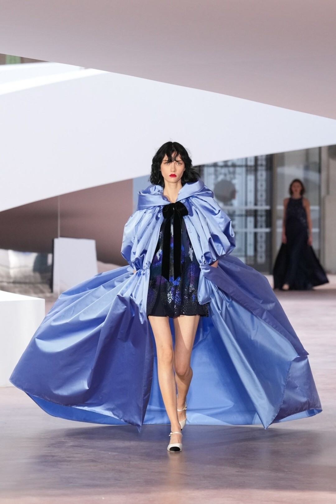 Продолжаем носить кейпы и накидки всех мастей: наш выбор — вариант из небесно-голубой тафты, которую показала на шоу модель София Стейнберг