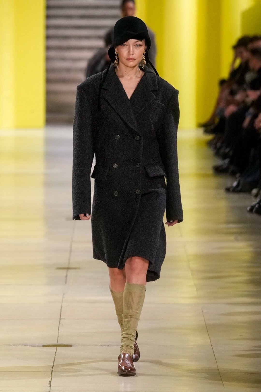 Джиджи Хадид (как обычно) вышла на подиум Miu Miu — на этот раз в плечистом пальто с батиного плеча