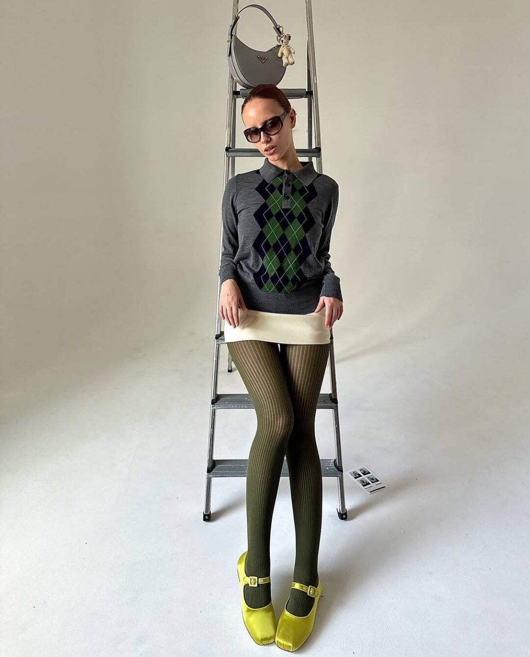 Фэшн-инфлюенсер Мари Гагеш мэтчит поло с изумрудными ромбиками с болотными колготками и brat-балетками