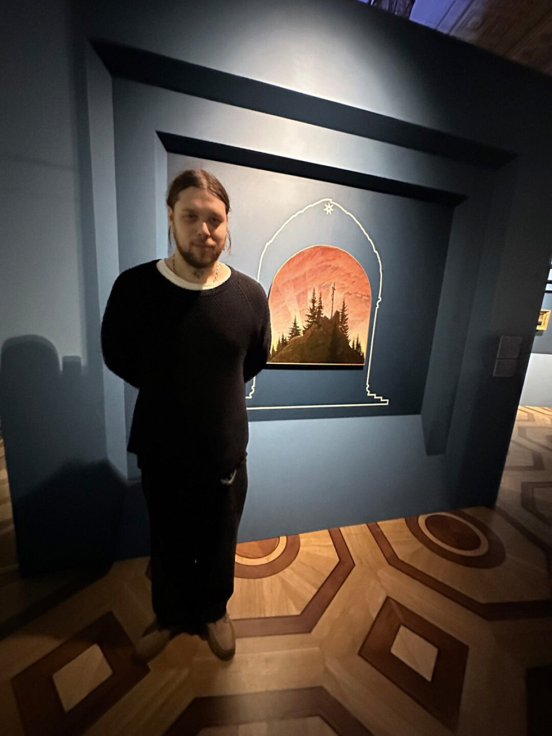 Шуля, преисполненный арт-пиететом, позирует у «Креста в горах» Каспара Давида Фридриха на выставке «Ландшафт души» в Эрмитаже