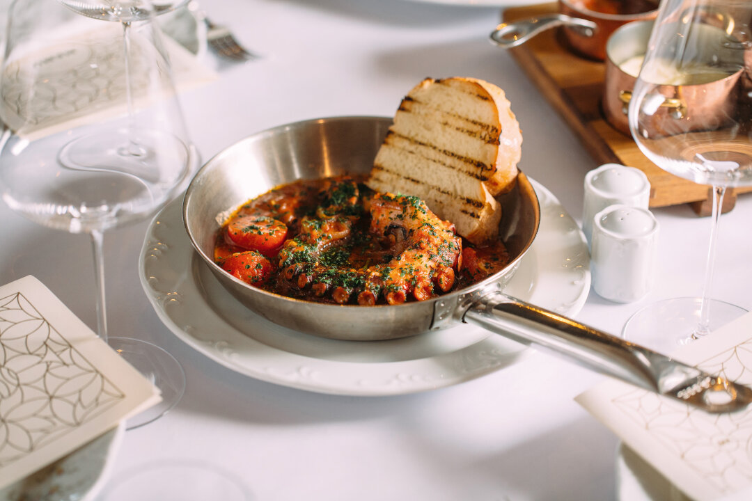 Щупальце осьминога оттеняет густой яркий томатный соус и домашний хлеб пульезе