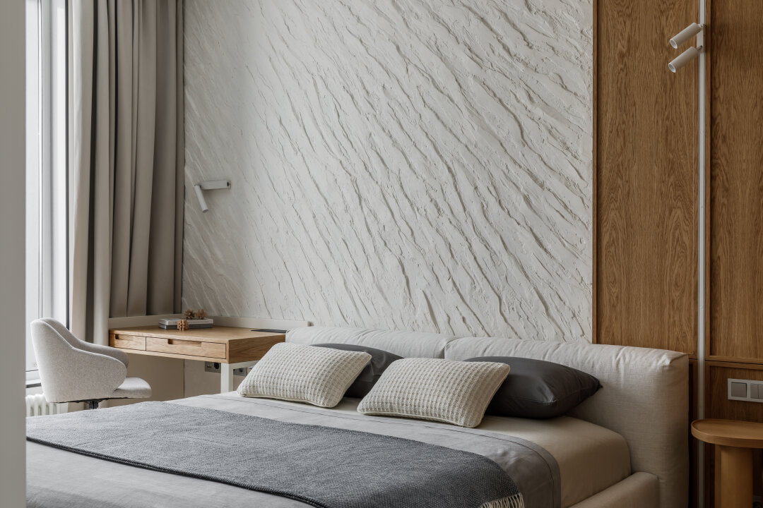 Каменная стена и обивка дивана в том же оттенке делают интерьер более монолитным