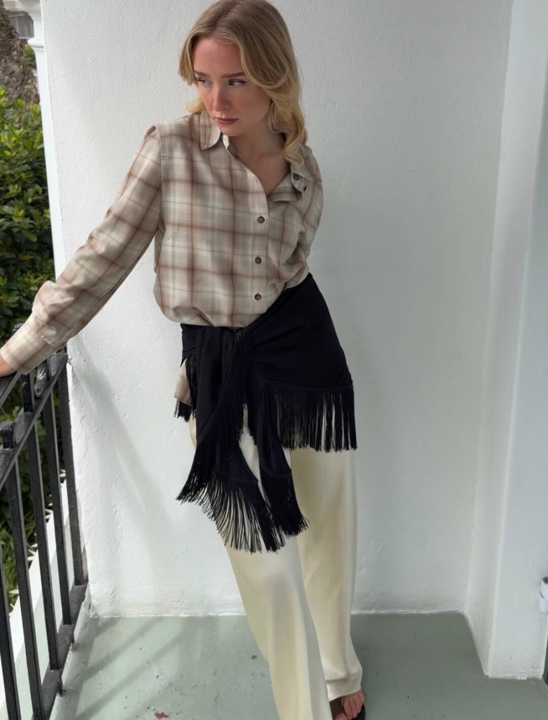 Фэшн-инфлюенсер Фанни Экстранд повязала контрастную косынку с бахромой поверх кэжуал-комбо клетчатой рубашки и белых джинсов