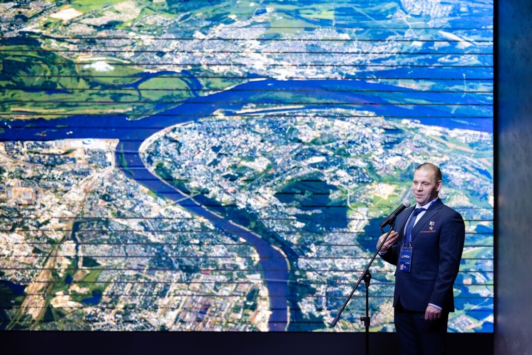 Иван Вагнер на фоне фотографии Нижнего Новгорода, сделанной им во время первого полета в космос
